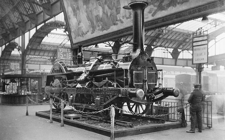 La locomotive Crampton n°80 lors de son exposition en gare de l’Est à Paris entre 1931 et 1946, carte postale, photo : Paul Gollemant, Collection Cité du Train